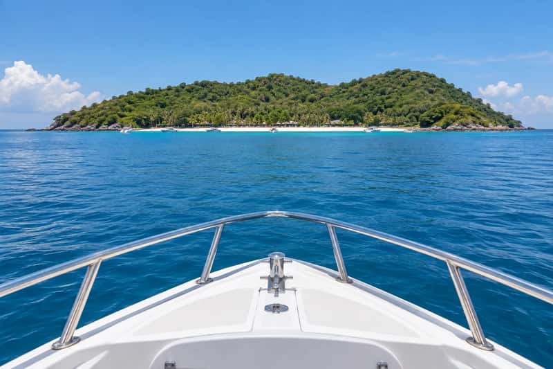 Speedboat approaching the green hills and beach of Coral Island